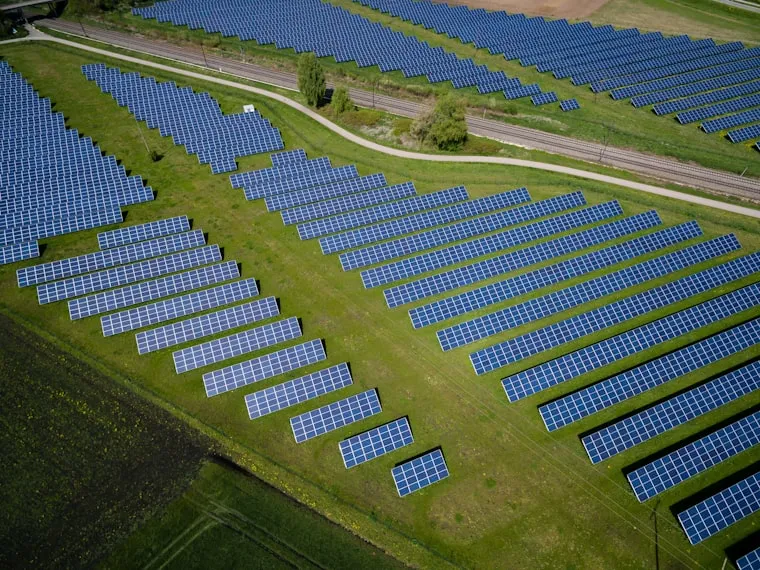 Vista aérea de una planta de paneles solares rodeada de zona verde