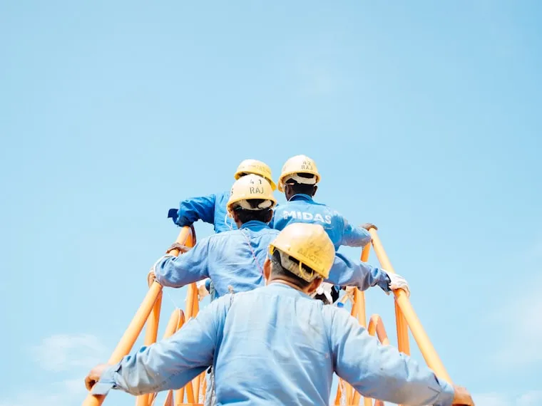 Cuadrilla de trabajadores con casco de seguridad sobre una estructura en altura